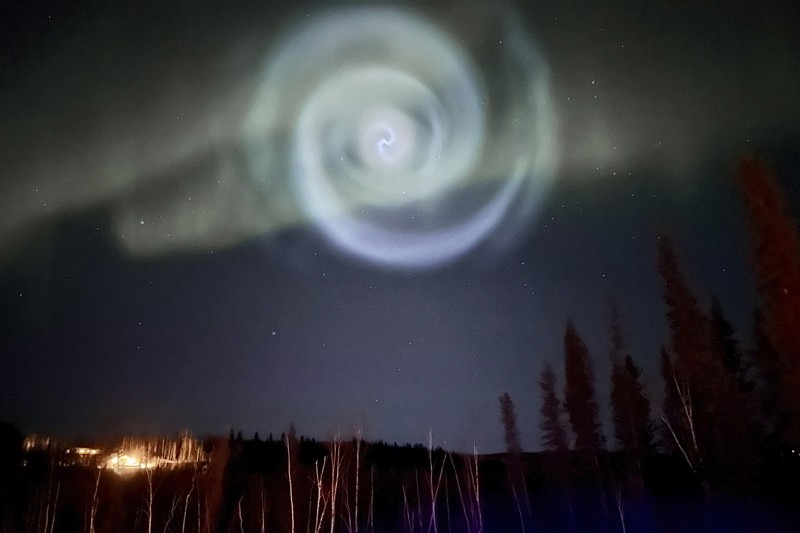 En esta foto proporcionada por Christopher Hayden, una espiral azul claro que se asemeja a una galaxia aparece en medio de la aurora durante unos minutos en los cielos de Alaska cerca de Fairbanks, el sábado 15 de abril de 2023