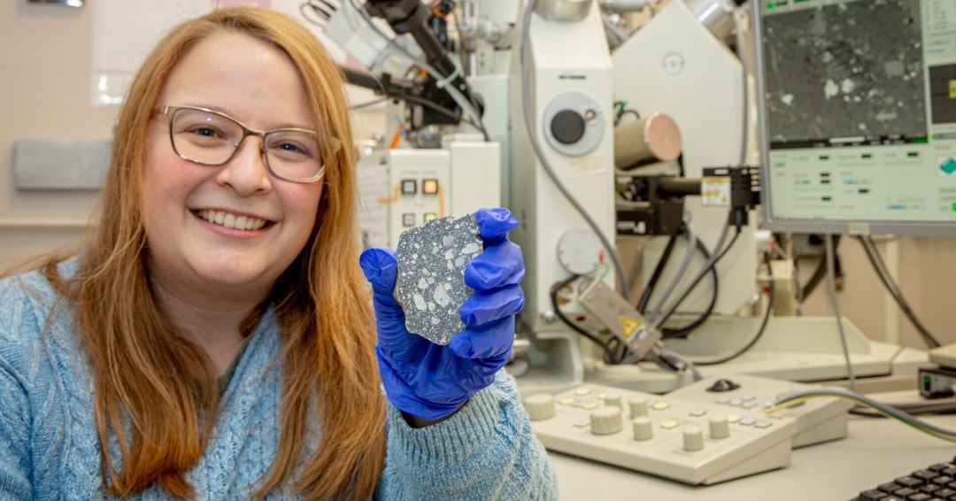 La becaria posdoctoral occidental Tara Hayden con un meteorito lunar